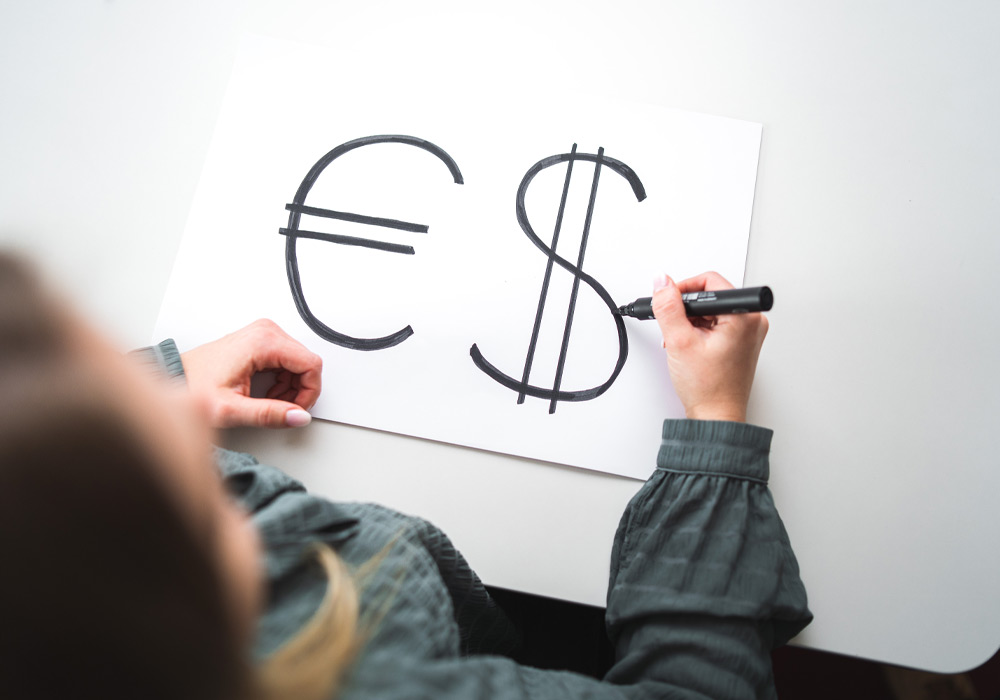 Hand zeichnet ein Euro und ein Dollar Zeichen auf weisses Papier